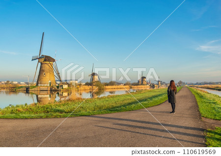 Dutch Windmill landscape at Kinderdijk Village Netherlands with woman tourist Dutch Windmill landscape at Kinderdijk Village Netherlands with woman tourist 110619569