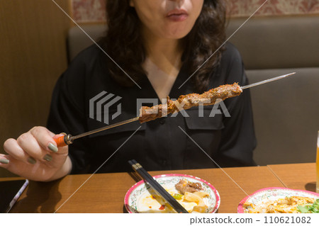 woman eating lamb skewers 110621082