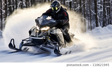 A man riding on a snowmobile through a snowy forest on a sunny winter day. Guy riding outside on a cold winter day. A man is riding on a snow mobile in a snowy forest. 110621945