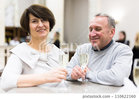 Mature man and woman drinking champagne in theater lobby 110622160