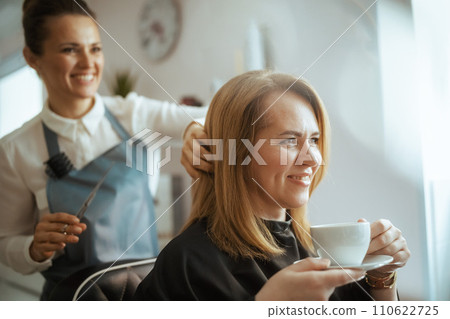 40 years old hair salon employee in beauty salon cutting hair 40 years old hair salon employee in beauty salon cutting hair 110622725