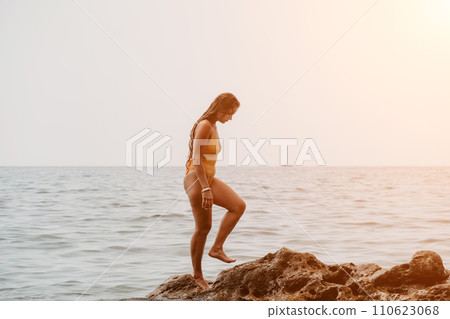 Woman travel sea. Happy tourist in hat enjoy taking picture outdoors for memories. Woman traveler posing on the beach at sea surrounded by volcanic mountains, sharing travel adventure journey 110623068