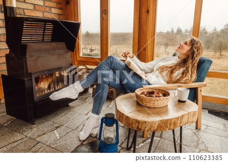 Woman Relaxing with Book at Indoor Terrace with Fireplace Woman Relaxing with Book at Indoor Terrace with Fireplace 110623385