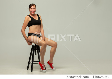 Attractive older woman 50 years old wearing stylish black underwear isolated on gray background. Attractive older woman 50 years old wearing stylish black underwear isolated on gray background. 110623949