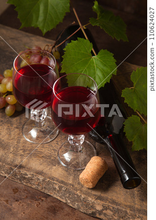 Still life with glasses of red wine and grapes on vintage wooden background.. 110624027