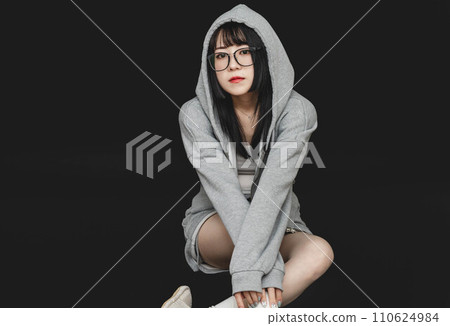黑色背景中穿著連帽衫的年輕女子 110624984