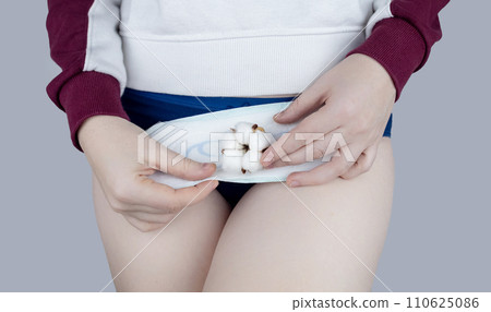 Sanitary napkin and cotton plant flower. The girl shows a cotton sanitary pad against the background of her panties. Concept of plastic-free products for women menstruation. Eco friendly products 110625086
