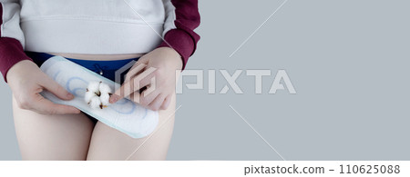 Sanitary napkin and cotton plant flower. The girl shows a cotton sanitary pad against the background of her panties. Concept of plastic-free products for women menstruation. Eco friendly products Sanitary napkin and cotton plant flower. The girl shows a cotton sanitary pad against the background of her panties. Concept of plastic-free products for women menstruation. Eco friendly products 110625088