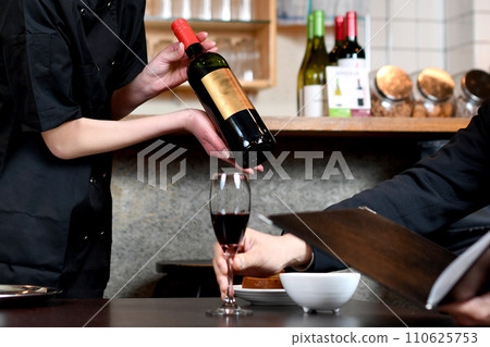 A female clerk explaining wine to a man at a restaurant A female clerk explaining wine to a man at a restaurant 110625753