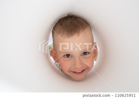 The face of a funny little boy looking into a paper hole. The face of a funny little boy looking into a paper hole. 110625951