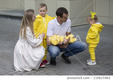 Mom and dad show the children a newborn baby. A baby has appeared in the family. Meeting your newborn brother or sister. Family with children at the maternity hospital. Mom and dad show the children a newborn baby. A baby has appeared in the family. Meeting your newborn brother or sister. Family with children at the maternity hospital. 110625962