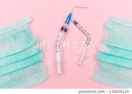 Broken Medical Syringe and Torn Medical Face Mask on the Pink Background Broken Medical Syringe and Torn Medical Face Mask on the Pink Background 110626224