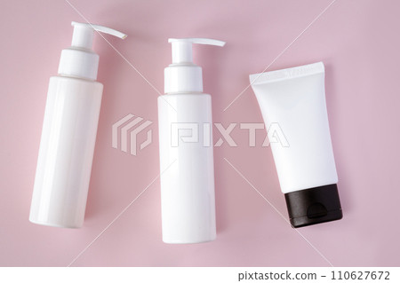 White bottles and tube of cosmetic products on pink background White bottles and tube of cosmetic products on pink background 110627672