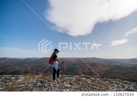 woman on mountain peak looking in beautiful mountain valley in autumn. Landscape with sporty young woman, blu sky in fall. Hiking. Nature 110627810