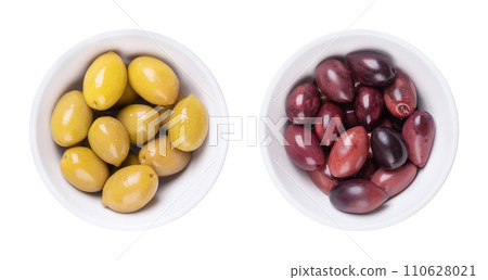 Green and Kalamata olives with pit, pickled whole, large Greek table olives, in white bowls. Green olives picked when still unripe, and Kalamata olives picked when ripe, both preserved in a brine. Green and Kalamata olives with pit, pickled whole, large Greek table olives, in white bowls. Green olives picked when still unripe, and Kalamata olives picked when ripe, both preserved in a brine. 110628021