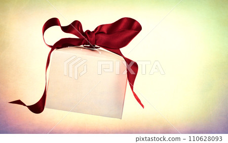 White gift box with a red bow on a vintage background with a dark vignette. 110628093
