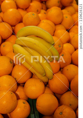 Branch of yellow ripe bananas and orange.Tropical fruits on sale. 110628121
