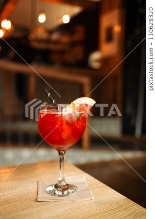 Orange cocktail with grapefruit, ice and rosemary in a transparent glass on a wooden table at style cafe 110628320