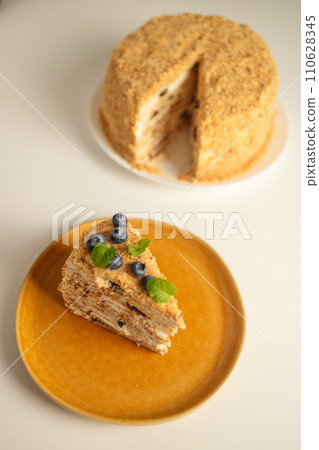 Homemade baked cake Napoleon, Millefeuille. Delicate custard cake garnished with berries and mint. On a gray concrete stone background. Homemade baked cake Napoleon, Millefeuille. Delicate custard cake garnished with berries and mint. On a gray concrete stone background. 110628345