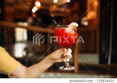 Popular bar summer ice alcoholic cocktails. Aperol Spritz and strawberry basil Margarita in glasses in woman hand at city cafe 110628415