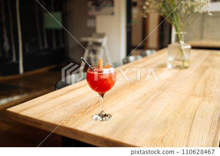 Orange cocktail with grapefruit, ice and rosemary in a transparent glass on a wooden table at style cafe Orange cocktail with grapefruit, ice and rosemary in a transparent glass on a wooden table at style cafe 110628467