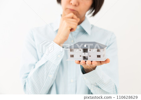 一位中年婦人拿著公寓大樓的模型，憂心忡忡。 110628629