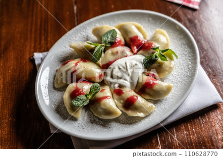 Eastern European traditional food dumplings - pierogi, varenyky, pirohy filled with strawberries and topped with jam 110628770