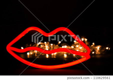 Blurry neon red lips close-up on a black isolated background. Blurry neon red lips close-up on a black isolated background. 110629561