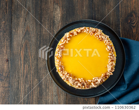 Lemon tart or lemon cake decorated chopped walnuts. Delicious whole lemon pie on wooden background. Aesthetic of traditional classic french lemon tart, recipe idea. Top view, copy space, rustic 110630362