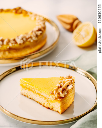 Piece of delicious vegan lemon tart or lemon cake, modernly decorated with walnuts on aesthetic plate. Aesthetic of traditional classic french lemon pie with lemon curd recipe. Vertical, copy space 110630363