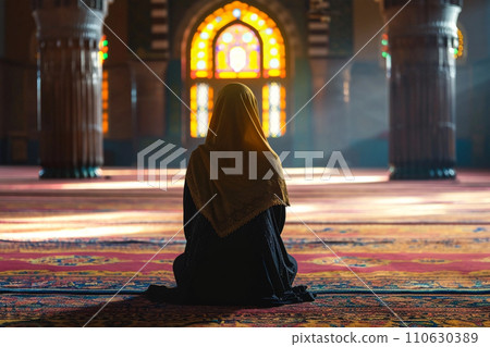 Muslim woman praying in mosque. Sunlight rays and haze through the window 110630389