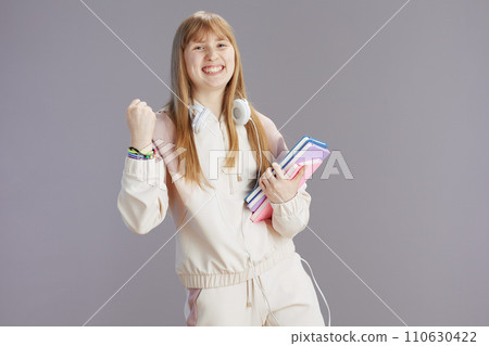 smiling trendy teen girl in beige tracksuit rejoicing 110630422