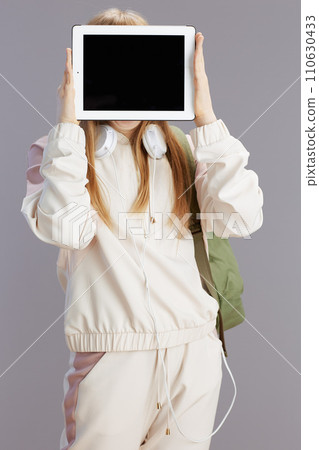 modern girl in beige tracksuit showing tablet PC blank screen 110630433