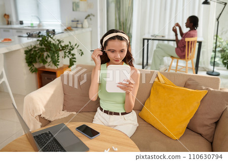 Teenage girl brushing eyebrows when getting ready for party or online class 110630794