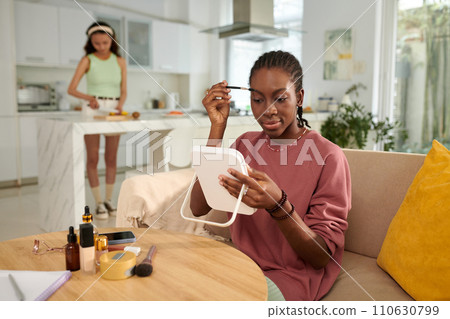 Smiling Black girl applying make-up when getting ready for school Smiling Black girl applying make-up when getting ready for school 110630799
