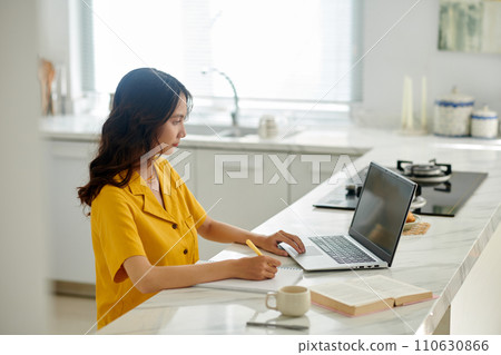 University student watching webinar and writing in planner 110630866