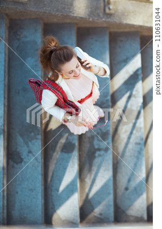 smiling woman in dress and jacket in city talking on phone 110631044
