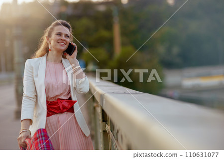 happy woman in dress and jacket in city talking on phone happy woman in dress and jacket in city talking on phone 110631077