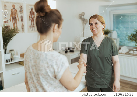 happy female therapist in massage cabinet shaking hands happy female therapist in massage cabinet shaking hands 110631535