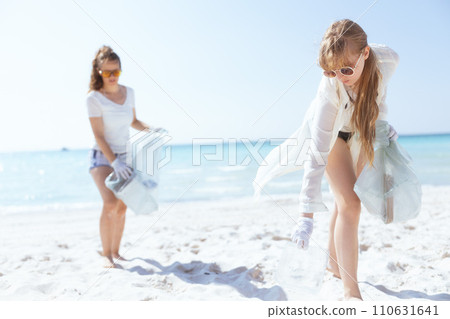concerned female volunteers on ocean shore collecting trash 110631641