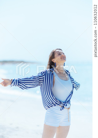 happy stylish woman on ocean coast rejoicing 110632012