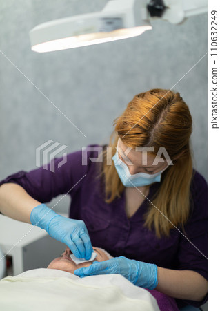The beautician works with a surgical mask and disposable gloves. The beautician works with a surgical mask and disposable gloves. 110632249
