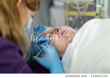 The beautician injects the product under her client's skin. 110632254