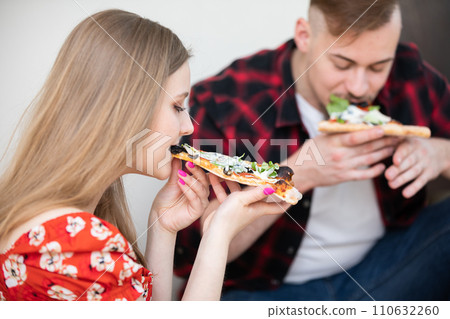 Close-up on two young people eating salami pizza. 110632260