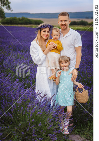In a lavender field, mom, dad, and two little daughters are enjoying a happy family moment 110632282