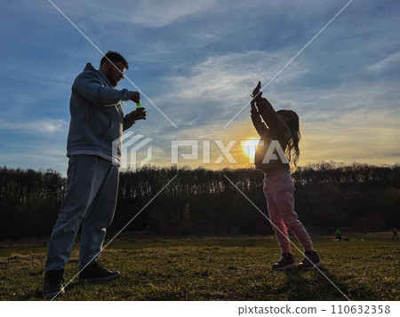 happy man with little girl playing with soap bubbles happy man with little girl playing with soap bubbles 110632358