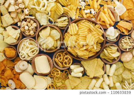 Colorful mix of salty snacks for beer varieties: chips and pretzels, onion rings and crackers. Non-healthy junk food background 110633839