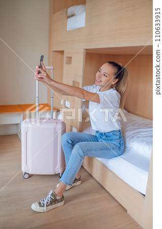Woman taking selfie after arriving at hotel room. 110633915