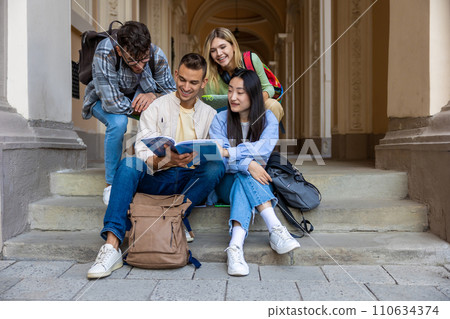 Students reading books studying or working on project while sitting on stairs of college campus. 110634374