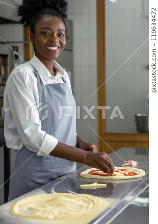 Dark-skinned woman preparing dough for pizza Dark-skinned woman preparing dough for pizza 110634472